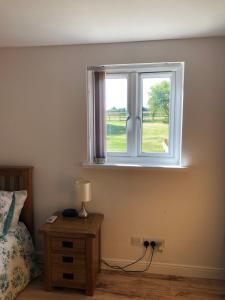 乌波斯顿The Barn的一间卧室设有窗户和一张带台灯的桌子