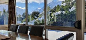 库克山村Aoraki Alpine Chalet的一间带桌子和大窗户的用餐室
