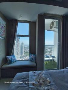 泗水The Paneya@Anderson Apartment的一间带靠窗座位的卧室,享有城市美景