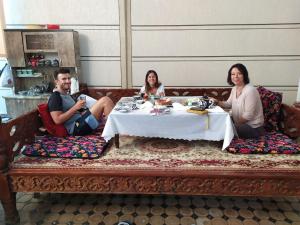 MargilanUvaysiy family guest house的三人坐在桌子旁
