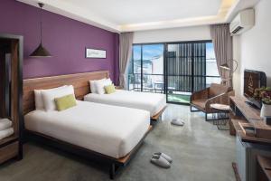 安帕瓦Amphawa Nanon Hotel的酒店客房设有两张床和一个阳台。