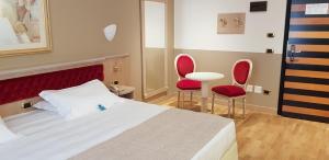 圣多纳托-米拉内塞桑塔芭芭拉酒店的一间卧室配有一张床和两张红色椅子