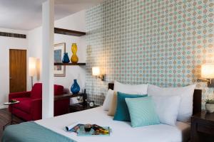 耶路撒冷普瑞玛罗亚尔绸酒店的一间卧室配有一张床和一张红色椅子