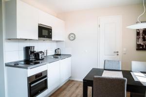 阿伦斯霍普Apartmentanlage Seezeichen的厨房配有白色橱柜和餐桌