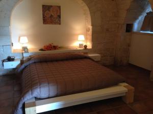 滨海波利尼亚诺Masseria Torre Catena Resort & Restaurant的一间卧室配有一张带两盏灯的床。