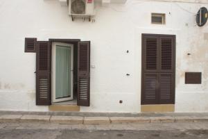 滨海波利尼亚诺Casa Nori的白色的建筑,设有棕色百叶窗和窗户
