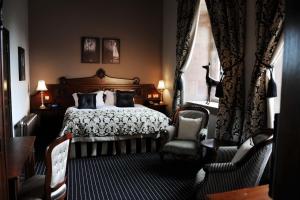 塔博雷Peckforton Castle的一间卧室配有一张床、两把椅子和一个窗户