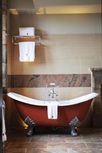 塔博雷Peckforton Castle的带浴缸的浴室,浴室的墙上配有毛巾