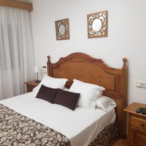 佩德罗－穆尼奥斯Hostal La Parada的卧室配有一张带白色床单和枕头的大床。