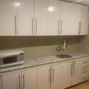 科威特豪维里1号特雷斯服务公寓的厨房配有白色橱柜、水槽和微波炉