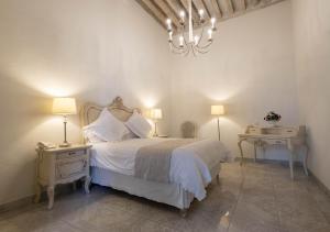 圣胡安德里奥雷赛卡酒店的卧室配有一张白色床、两张桌子和吊灯。