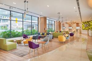 胡志明市Holiday Inn & Suites Saigon Airport, an IHG Hotel的大堂设有色彩缤纷的桌椅和窗户。