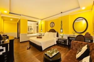 胡志明市Adora Art Hotel的卧室拥有黄色的墙壁,配有一张床和一张沙发