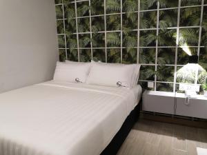 八打灵再也Apex Boutique Hotel @ Bandar Sunway的花草墙的房间里一张白色的床