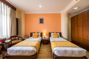 加德满都Airport Hotel的橙色墙壁的酒店客房内的两张床