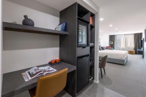 堪培拉Deco Hotel Canberra的一间带书桌的房间和一间带床的卧室