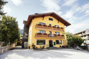 库夫施泰因Hotel VIKTORIAS HOME Kufstein的黄色的建筑,带有木屋顶