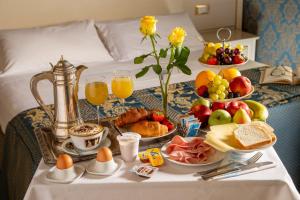 罗马Residenza Canova Tadolini - Guesthouse的床上的早餐桌,包括早餐食品和饮料