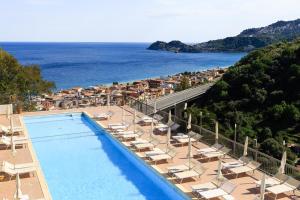勒托阳尼安塔芮丝酒店的毗邻大海的带椅子和遮阳伞的游泳池