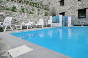 VetrianoCarpe diem Colognora的一座带白色椅子和桌子的游泳池以及一座建筑