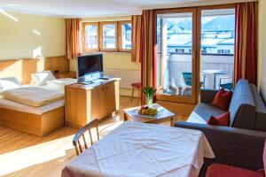 巴特霍夫加施泰因莫努斯公寓酒店的客厅配有床、沙发和电视。