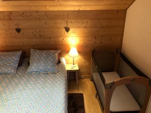 MarignierAU COEUR DES ALPES的一间卧室配有一张床、一盏灯和一把椅子