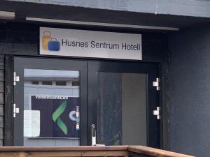 HusnesHusnes Sentrum Hotell的建筑玻璃门上方的标志
