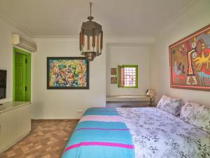 马拉喀什Riad Volubilis的卧室配有一张床,墙上挂有绘画作品