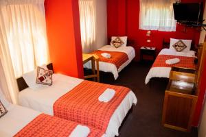 普诺帕查套房旅舍的酒店客房,设有三张床和红色的墙壁