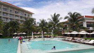 岘港Ocean Apartment Spa & Golf Danang的度假村内有人员在游泳池游泳