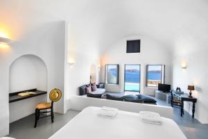 阿克罗蒂里Grand Ambassador Santorini Hotel的一间卧室配有一张床、一张桌子和一张沙发