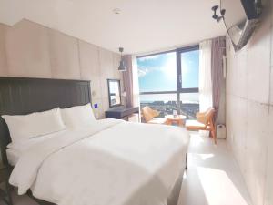 西归浦市Hotel Stay Interview Jeju的配有大窗户的客房内的白色床