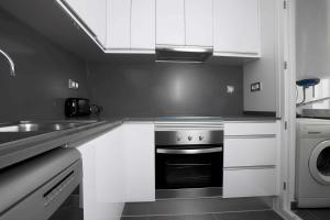 锡切斯Apartamentos Sunway Talaia的黑白厨房配有炉灶和水槽