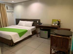 宿务宿务岛R马波罗酒店的一间卧室配有一张床、一张桌子和一张桌子