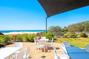 黄金海岸可伦宾海滩沙堡酒店的一个带白色桌椅的庭院和海滩