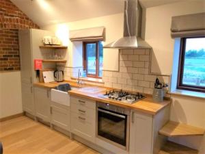 EllinghamBlashford Manor Holiday Cottage - The Dartmoor Cottage的厨房配有白色橱柜和炉灶烤箱。