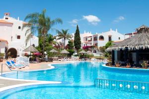 圣米格尔德阿沃纳球道俱乐部酒店的度假村的游泳池,配有椅子和遮阳伞