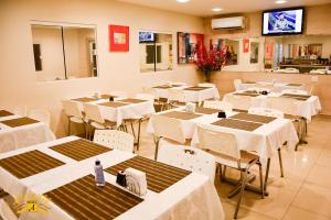 马卡帕Atalanta Hotel的餐厅设有白色的桌椅和电视。