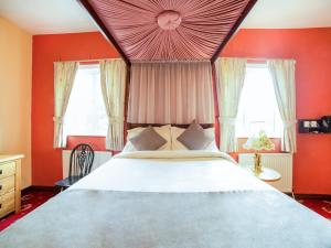 泰恩河畔纽卡斯尔OYO The Royal Hotel的一间卧室设有一张大床,拥有红色的墙壁和窗户。