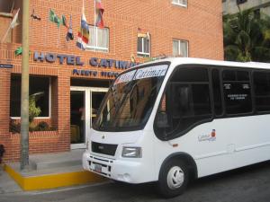 迈克蒂亚Hotel Catimar的停在酒店大楼前的一辆白色巴士