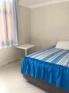 萨尔瓦多Propriedade aconchego de família的一间卧室配有一张带蓝色床单的床和一张桌子。