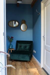 奈梅亨Mini appartement De Fabriek的蓝色房间中的绿色沙发,配有两面镜子