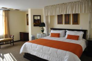 拉塔昆加MAK INN HOUSE的一间卧室配有一张带橙色和白色枕头的大床