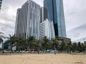 岘港Căn hộ nghỉ dưỡng Mường Thanh apartment的棕榈树海滩和高楼