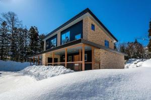 白马村Phoenix Chalets by Hakuba Hospitality Group的雪中的一个砖屋