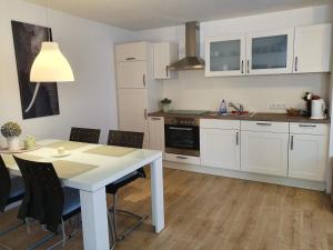 辛根Ferienwohnung Schwartz的厨房配有白色橱柜和桌椅