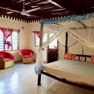 蒙巴萨A wonderful Beach property in Diani Beach Kenya.a dream holiday place.的一间卧室配有一张天蓬床和两把椅子