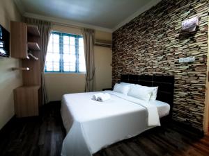 古晋6BR Single Storey Tabuan Jaya By Natol Homestay的卧室配有一张白色的大床和石墙