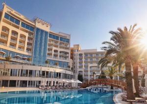 布德瓦豪华会议及水疗度假酒店的一座带游泳池、棕榈树和建筑的度假村