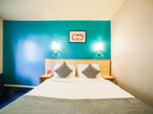 ThrussingtonOYO Sunrise Hotel, A46 N Leicester的一间卧室设有一张蓝色墙壁的大床